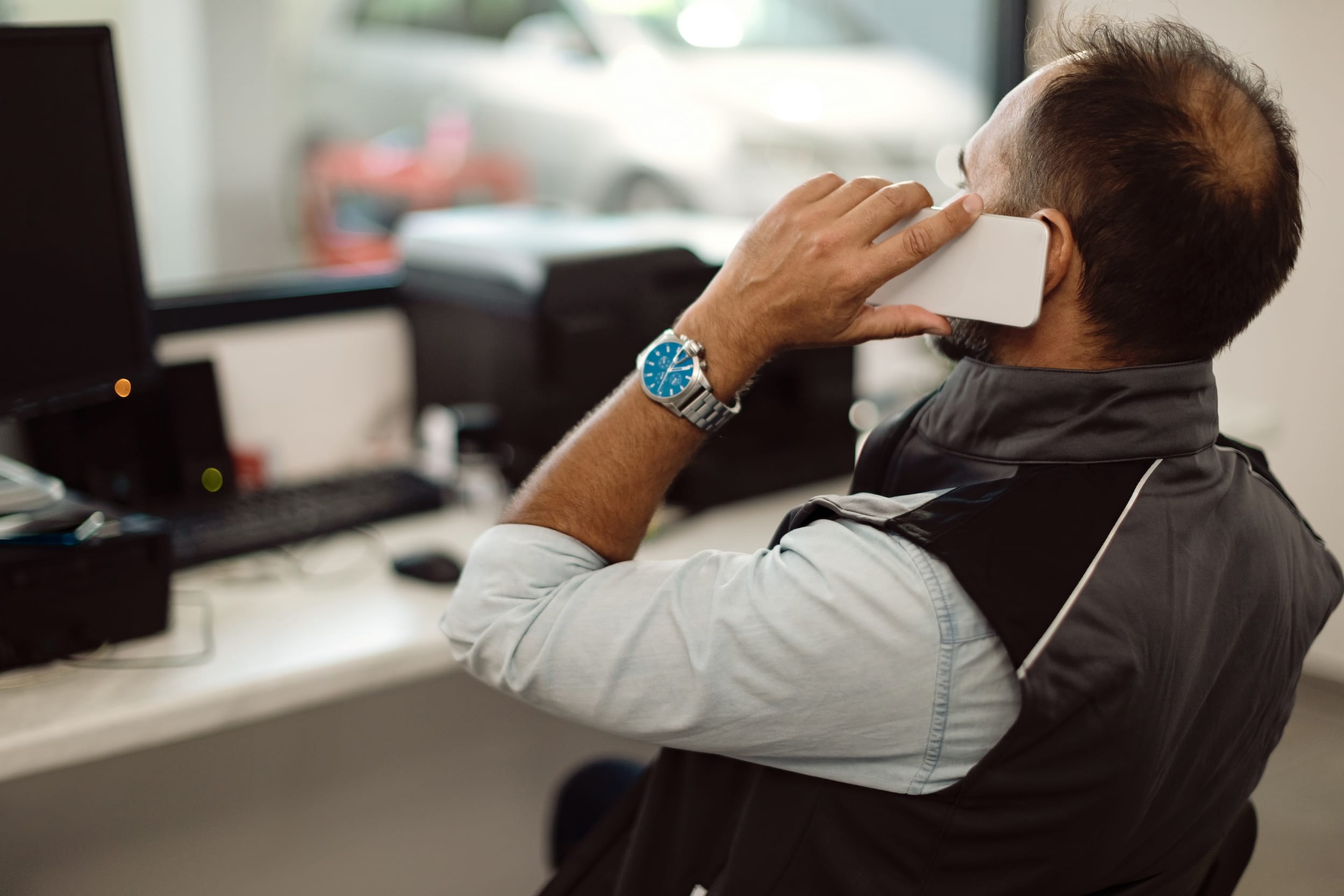 Auto mechanic talking on the phone at workshop’s office.